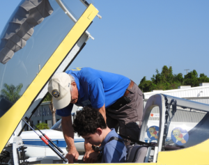 7372 EAA Chapter 534 pilot Steve Tilford gets Young Eagle Luke Naylor buckled in for his flight.
